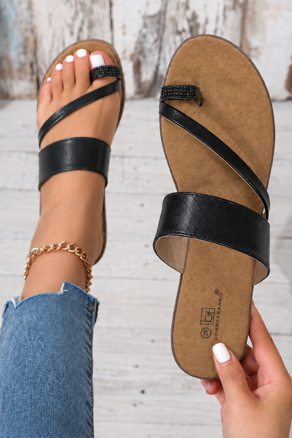 Sandalias negras con la uña de la mano blanca